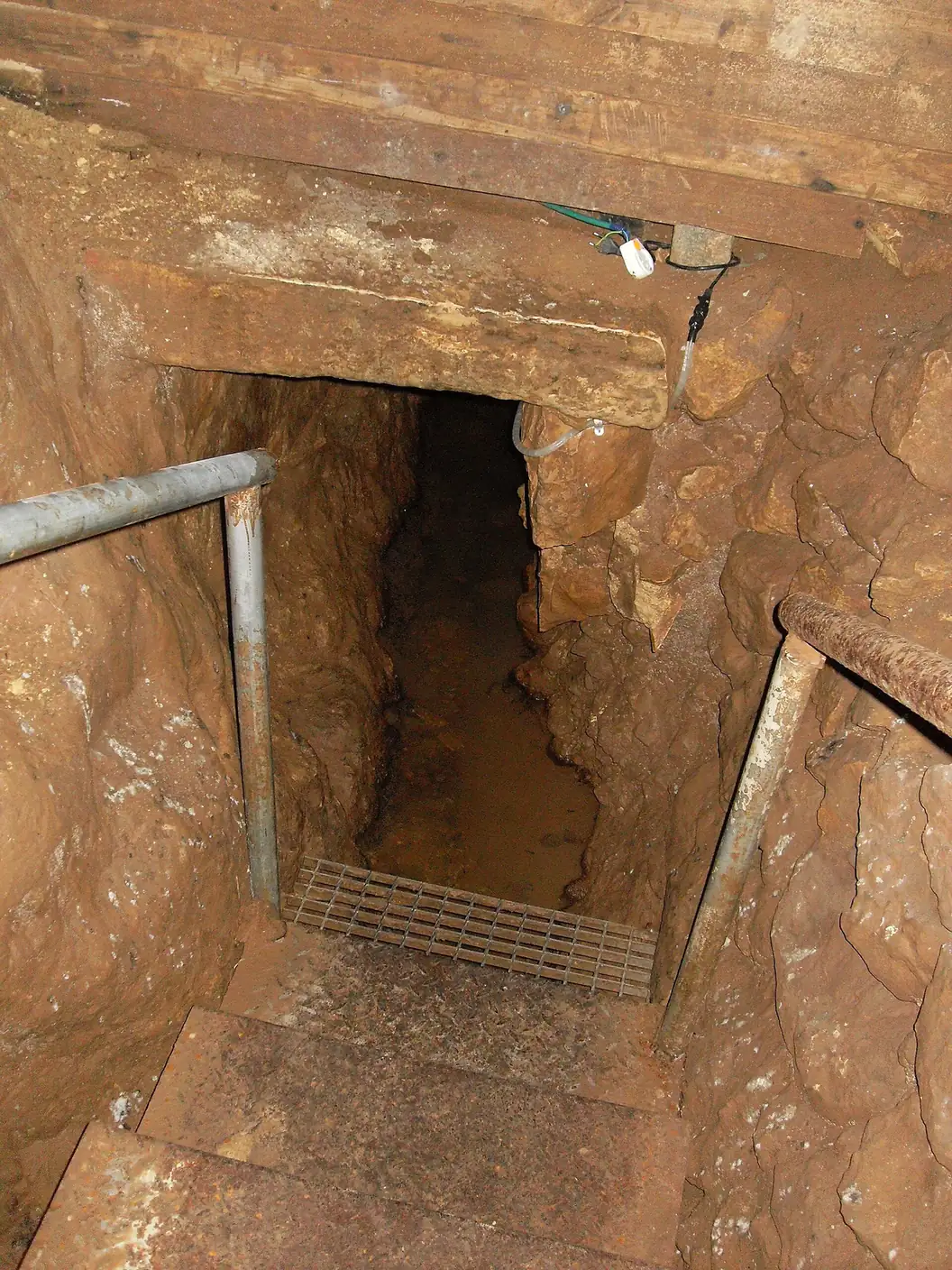 Stone steps and a handrail leading down into the rock-cut tunnel of the Biyar Aqueduct