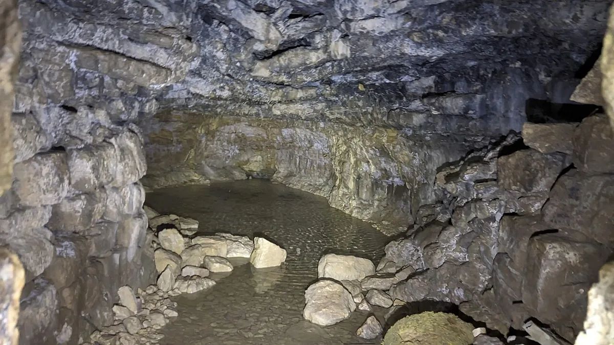 Ein Hubela spring at Bat Ayin: a large outdoor pool beside a small stone building over the spring tunnel